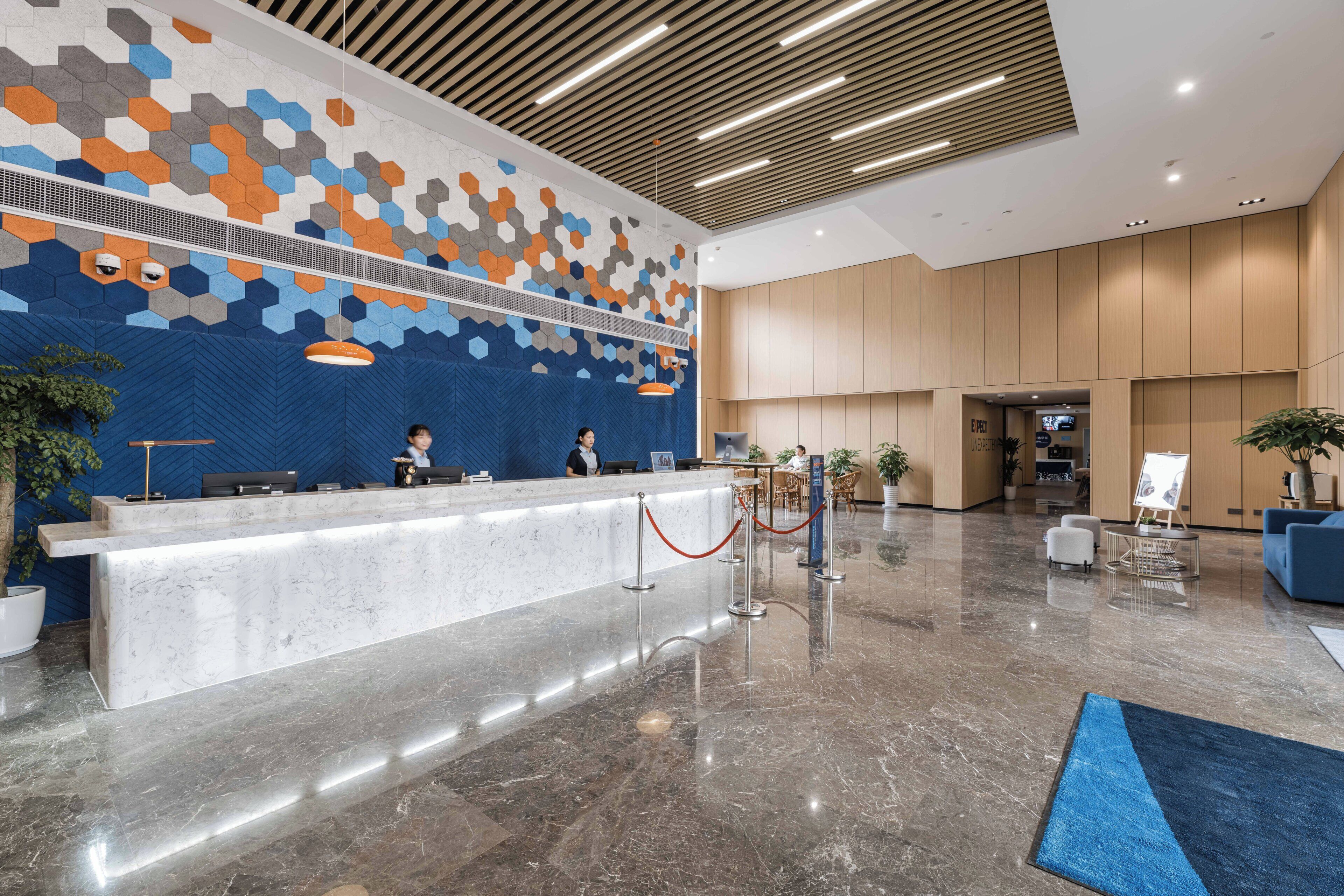 A modern reception area with a marble counter, a patterned wall, and a wooden ceiling.
