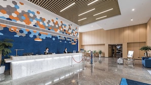 A modern reception area with a marble counter, a patterned wall, and a wooden ceiling. - Holiday Inn Express Pudong Chuansha by IHG (Shanghai)