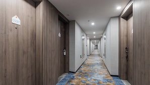 A hotel corridor with wooden doors, numbered room signs, and a patterned carpet. - Holiday Inn Express Pudong Chuansha by IHG (Shanghai)