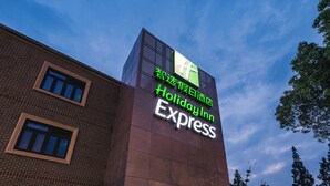 Ein Schild von Holiday Inn Express an einem Gebäude, bewölkter Himmel.