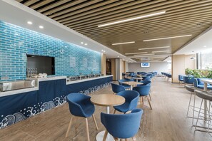 A modern cafe with blue-brick walls, wooden ceiling, and blue chairs.