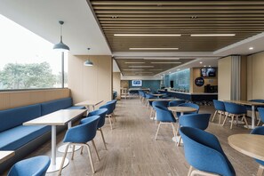 Un caffè moderno con pavimento in legno, sedute blu e vista sull'esterno.