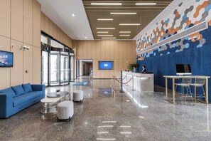 Una hall moderna con reception, area salotto e un ampio schermo digitale.