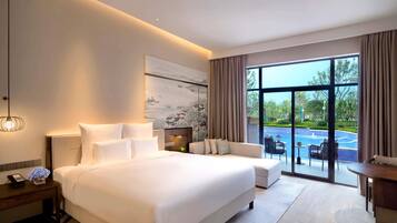 Habitación de hotel moderna con una cama grande, un sofá, una mesa de comedor y vista a una piscina.