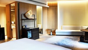 A hotel room with two beds, a sofa, a small table, a minibar, and a mirror. - Pullman Yueyang Hotel (Yueyang)