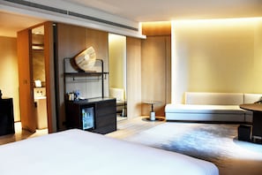 A hotel room with two beds, a sofa, a small table, a minibar, and a mirror. - Pullman Yueyang Hotel (Yueyang)