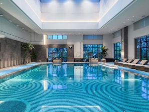 An indoor swimming pool with a tiled floor, seating areas, and large windows. - Pullman Yueyang Hotel (Yueyang)