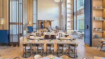 Un restaurante espacioso con techos altos, ventanas grandes y mobiliario moderno.