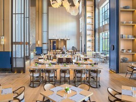 Un restaurante espacioso con techos altos, ventanas grandes y mobiliario moderno.