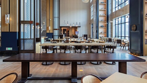 Un comedor amplio con techos altos y decoración moderna, que incluye lámparas colgantes y una mesa central.