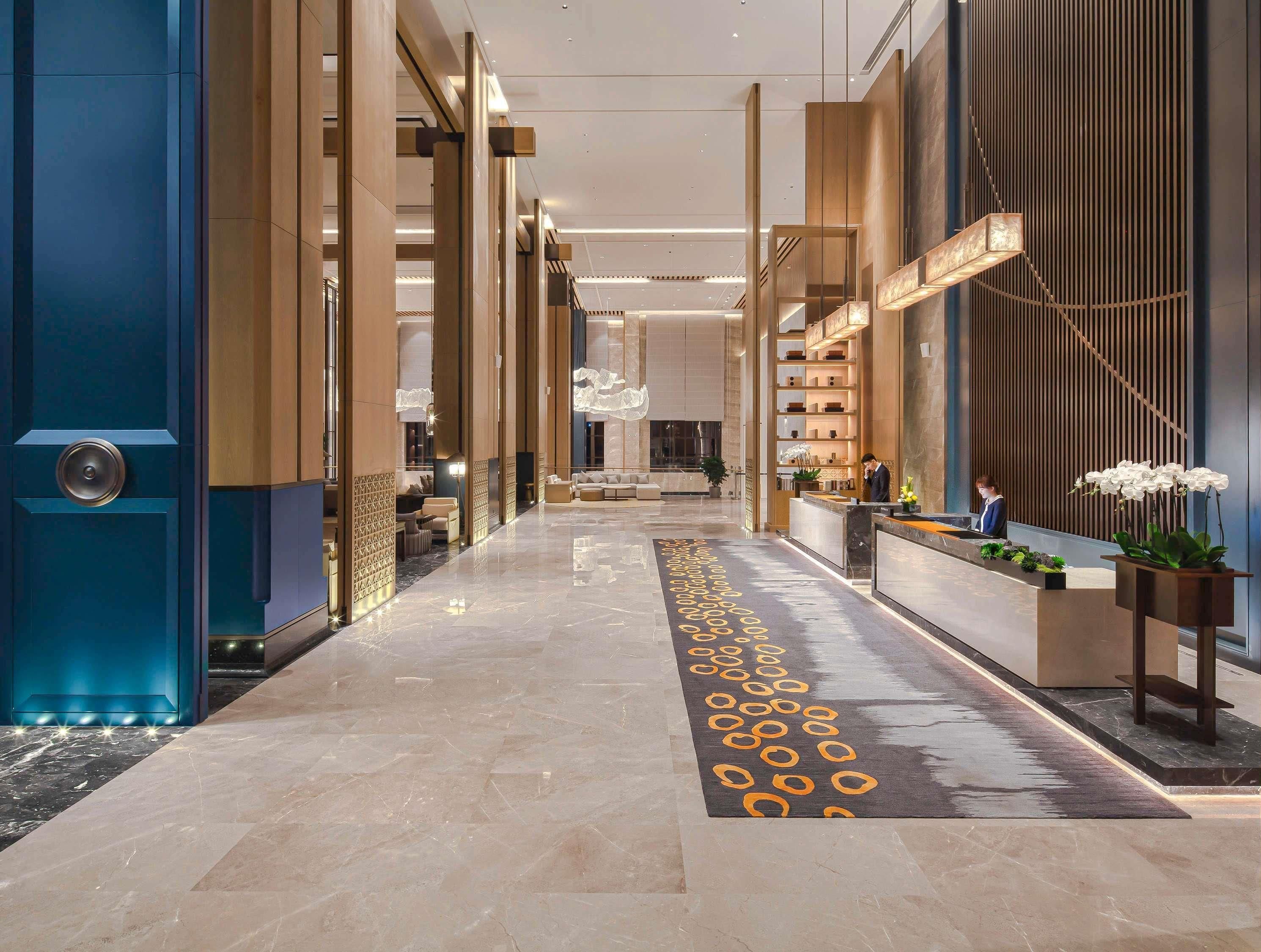 Un hall de hotel con suelo de mármol, mostrador de recepción y decoración moderna.