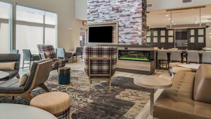 Un moderno vestíbulo de hotel con chimenea, asientos cómodos y una gran pantalla de televisión.