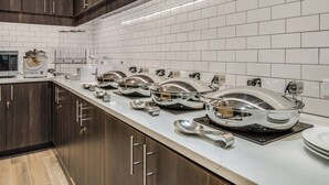 Una cocina moderna con electrodomésticos de acero inoxidable, salpicadero de azulejos blancos y armarios de madera.