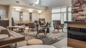 Un moderno vestíbulo de hotel con asientos cómodos, un mostrador de recepción y grandes ventanales.