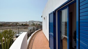 Een balkon met uitzicht op een kustplaatsje, een blauwe deur en een betegelde vloer.