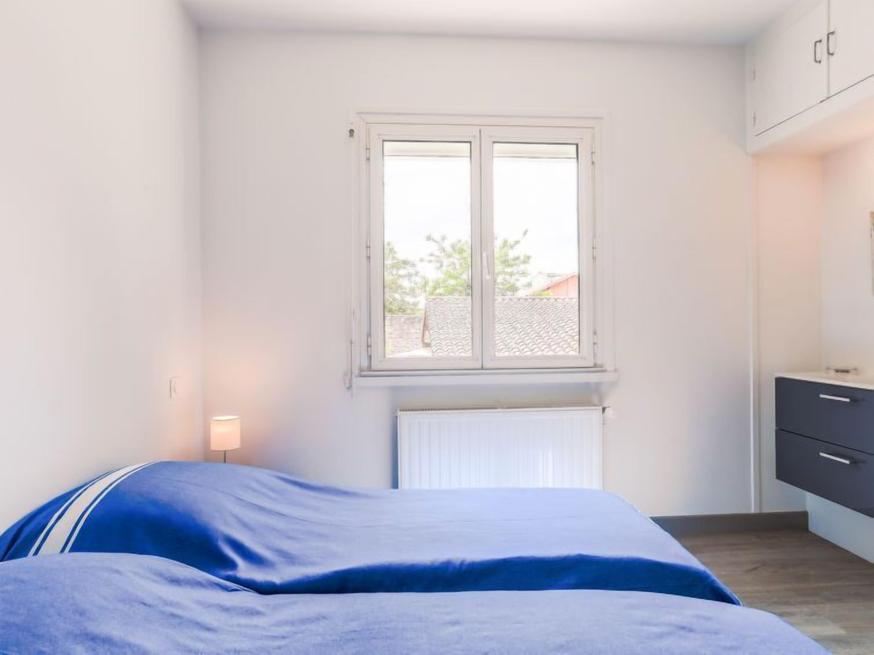 Une chambre à coucher avec un lit, une fenêtre, un radiateur et une armoire.