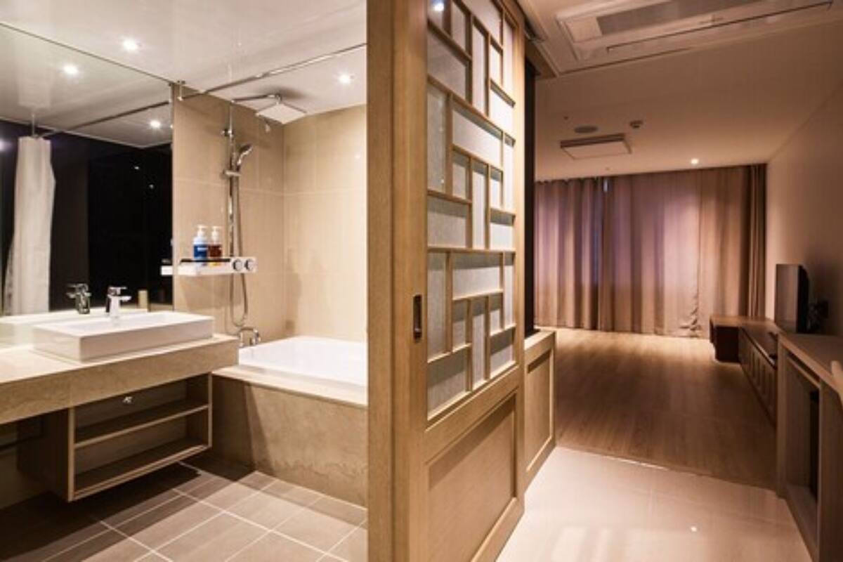 A modern bathroom with a large mirror, a bathtub, and a shower.