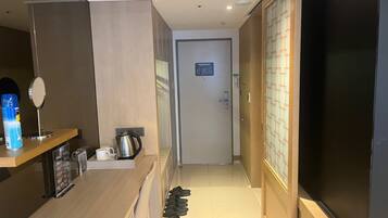 Un pasillo de hotel con un mostrador de madera, un hervidor, una cafetera y un zapatero.