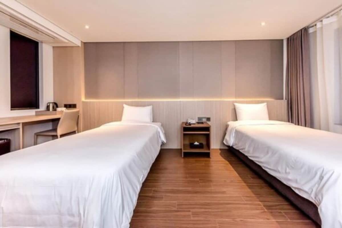 Una habitación de hotel con dos camas individuales, un escritorio y una silla.