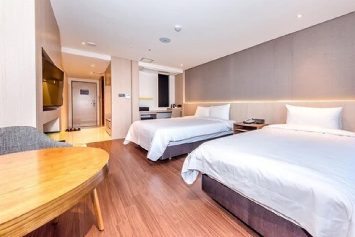 Habitación de hotel con dos camas, un escritorio y una kitchenette.