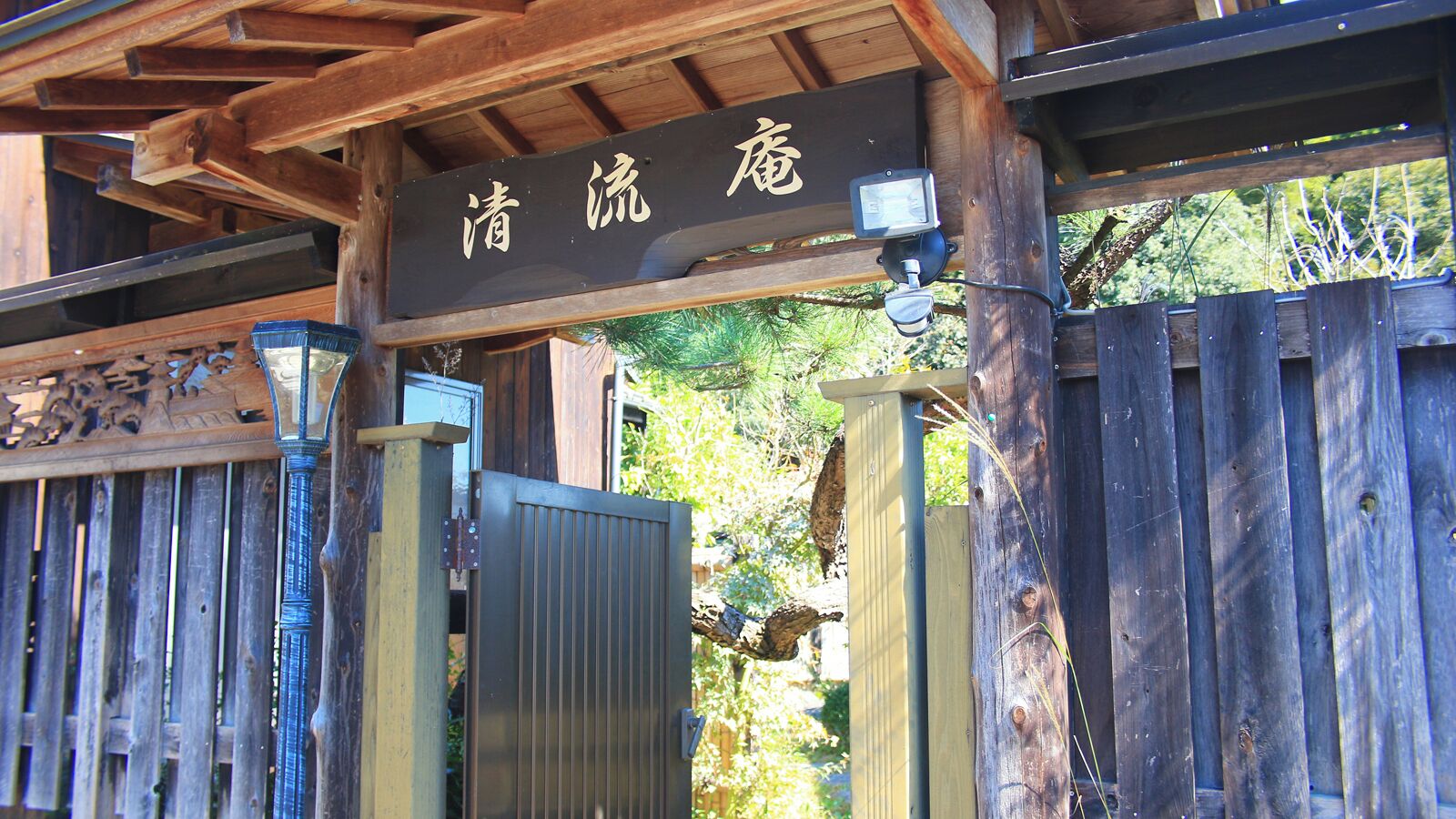 Un cancello in legno con un cartello sopra, un cancello in metallo e una recinzione in legno.