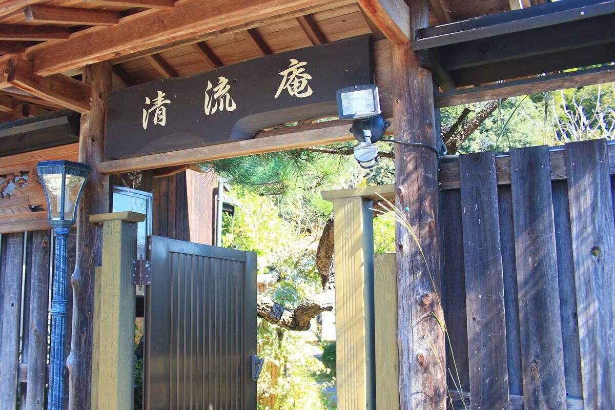 A wooden gate with a sign above it, a metal gate, and a wooden fence.