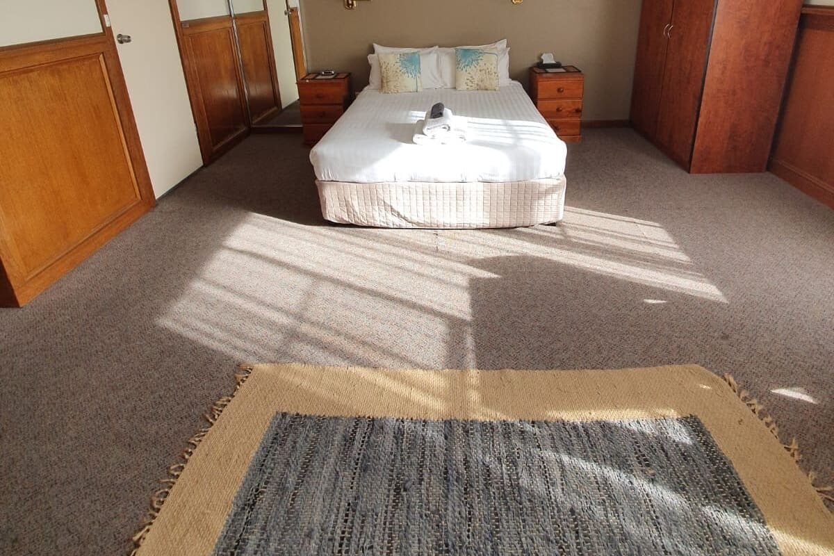 A bedroom with a bed, two bedside tables, a wardrobe, and a ceiling light.