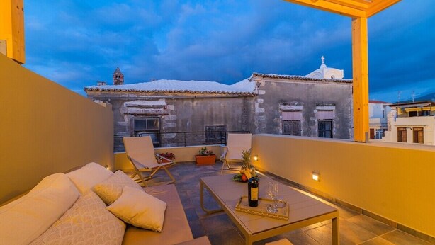 A rooftop terrace with a sofa, chairs, a table, and a bottle of wine. - Anatoli Residence - in the Old Town of Rethymno (Rethymno)