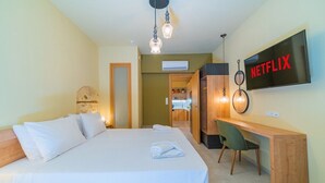 A hotel room with a bed, a desk, a chair, a TV, and a wall-mounted Netflix sign. - Anatoli Residence - in the Old Town of Rethymno (Rethymno)