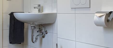 A modern bathroom with a white sink, toilet, and a mirror above the sink.