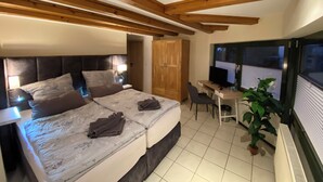 Ein Schlafzimmer mit Bett, Nachttischen, Schreibtisch, Stuhl und einer Zimmerpflanze.