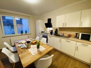 Une cuisine compacte comprenant une table à manger, des chaises, une machine à café, un four à micro-ondes et des placards.