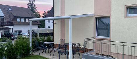 Ein Wohngebäude mit einer überdachten Terrasse und Sitzgelegenheiten im Freien.