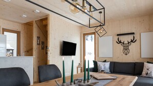 Un interior moderno con una mesa de comedor de madera, velas verdes y un televisor montado.