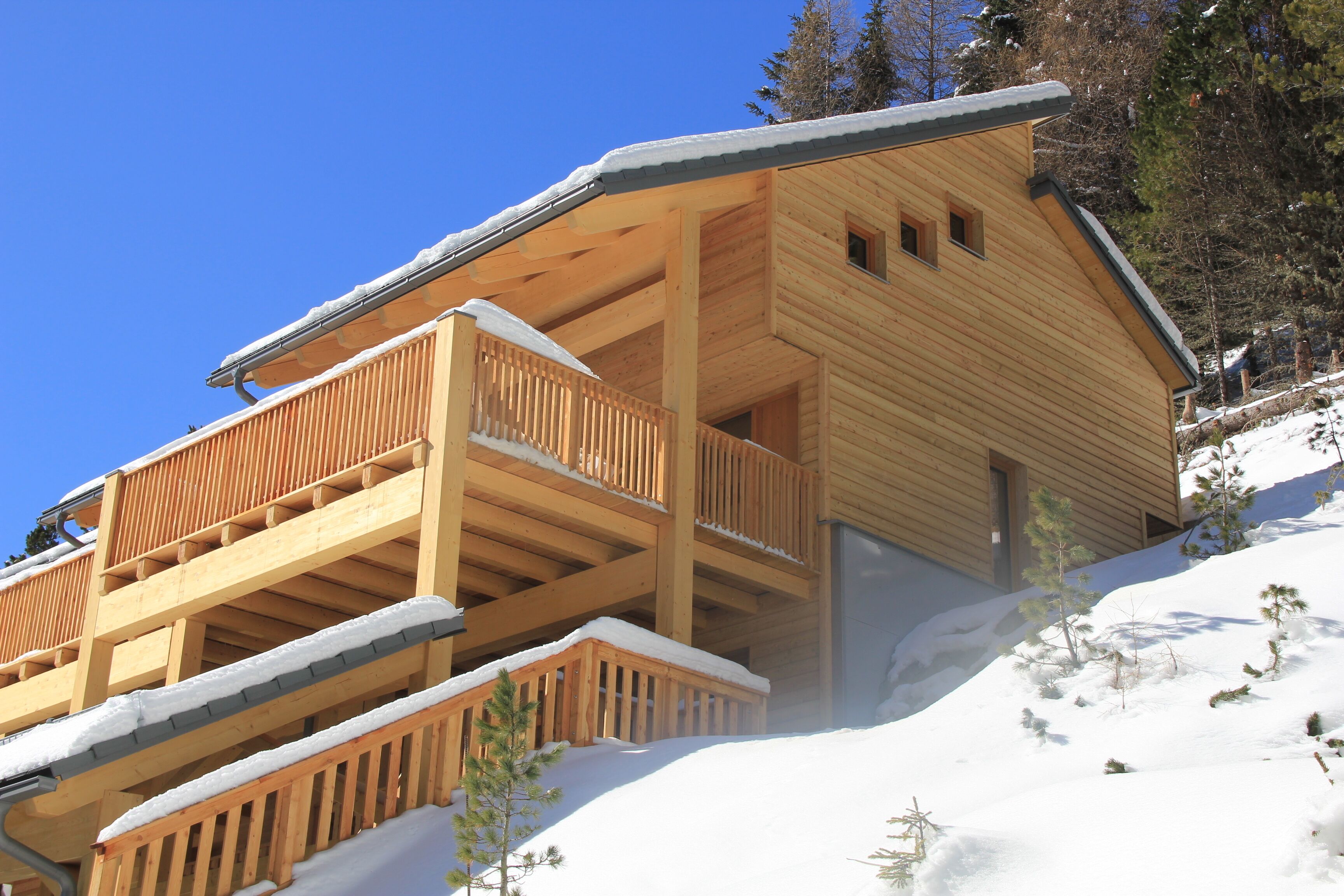 Un chalet en bois doté d’un balcon, niché au cœur d’un paysage enneigé.