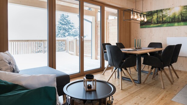 Un interior de madera con una mesa de comedor, sillas y una mesa redonda con una vela.