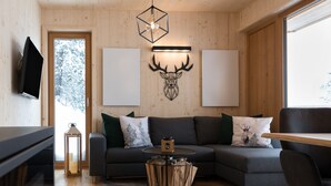 Una sala de estar moderna con un sofá modular, una mesa de centro redonda y un ciervo montado como decoración de pared.