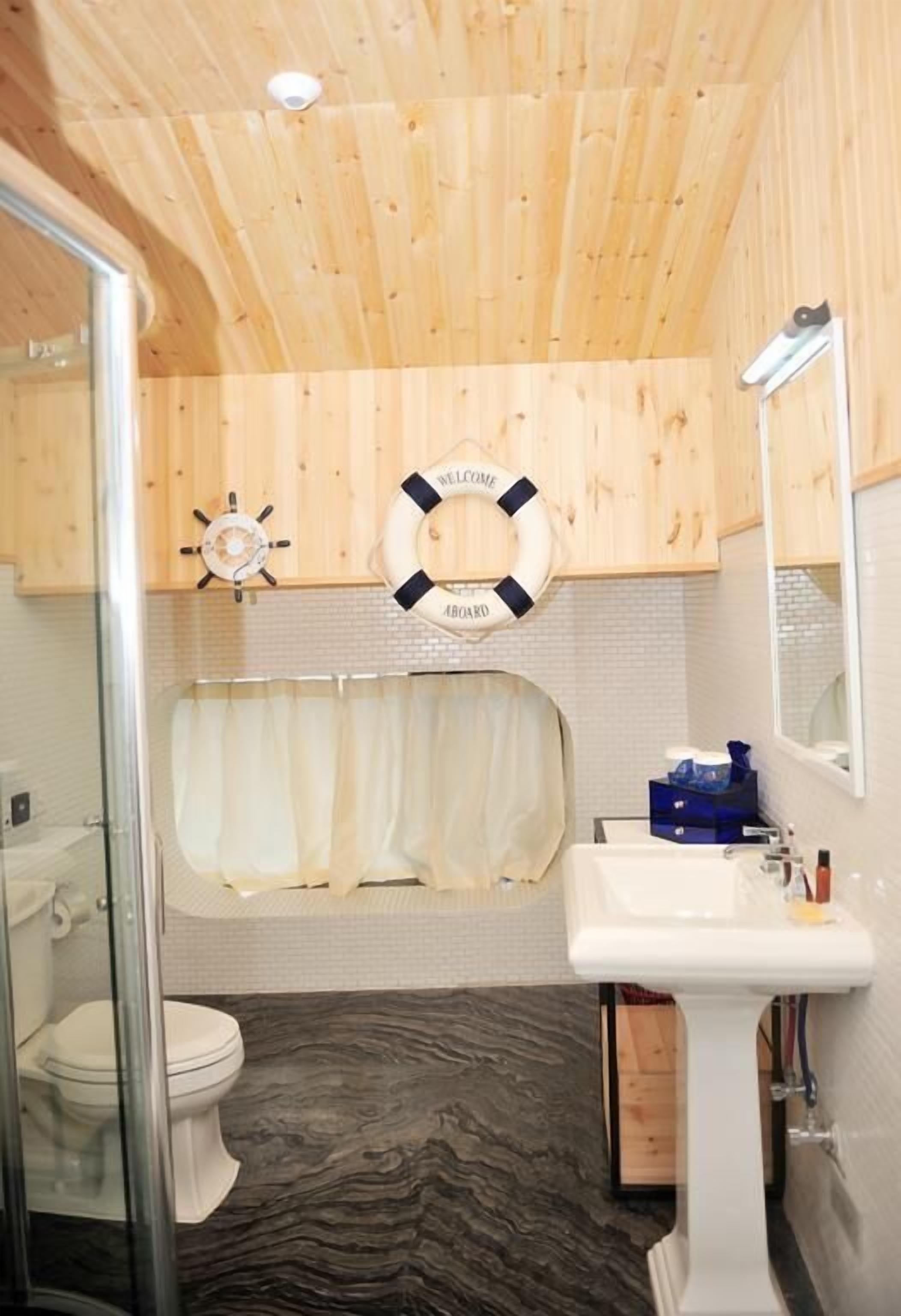 Un baño con techo de madera, una bañera, un lavabo y un inodoro.