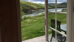 Et værelse med stort vindue med udsigt over en flod og grønt landskab.