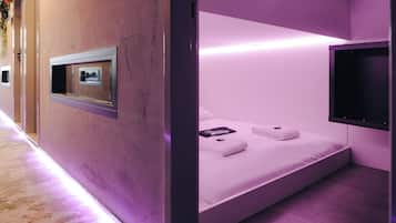 Ein modernes Zimmer mit Bett, einem Wand-Fernseher und einem kleinen Fenster.