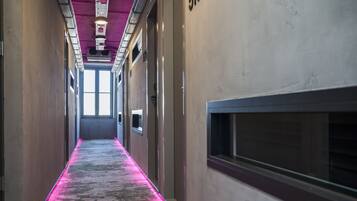 A hallway with a carpeted floor and a purple light strip running down the center.