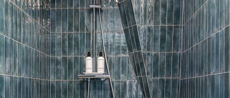 A bathroom with dark blue tiled walls, a showerhead, and a handheld shower attachment.