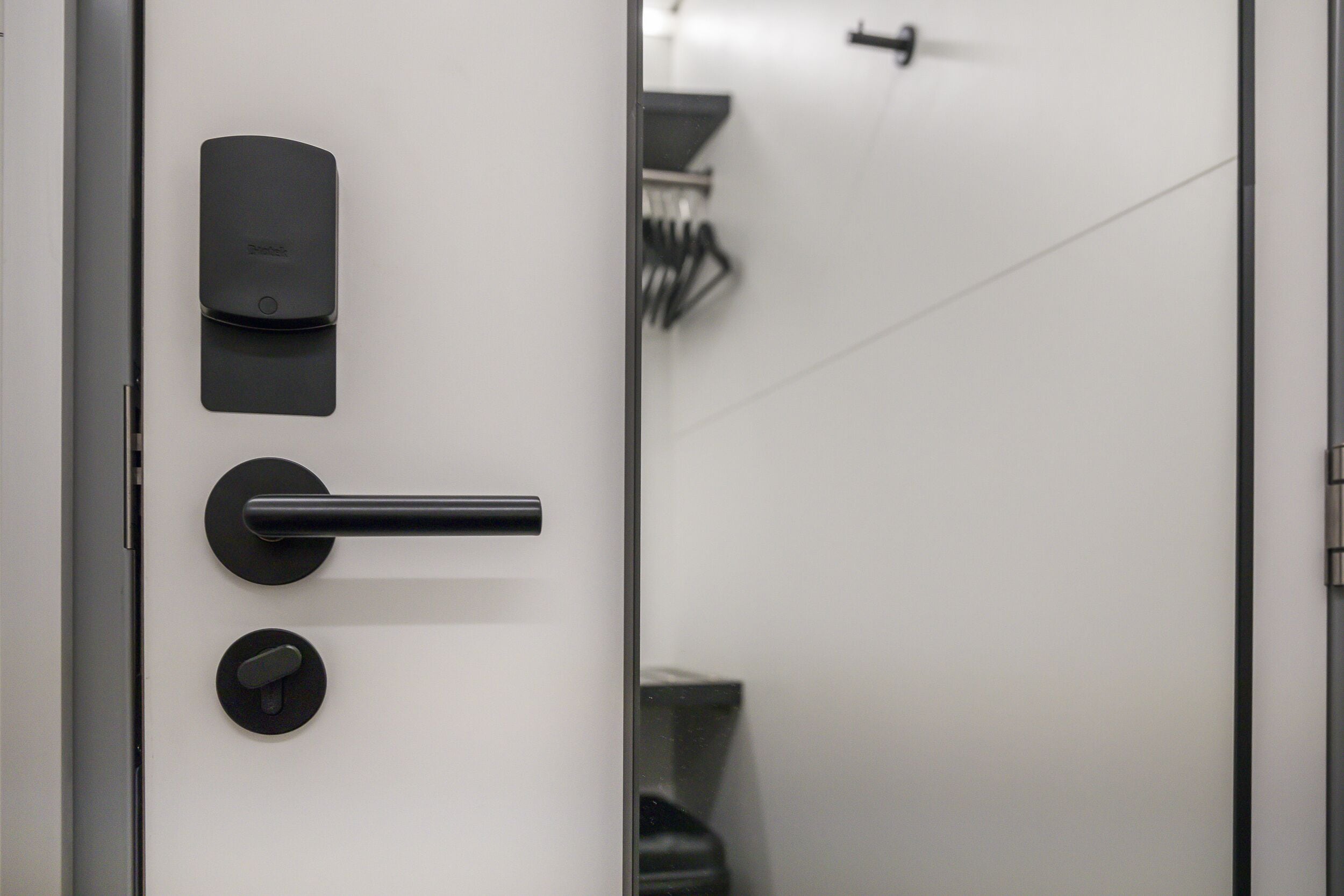 A modern door with a keycard reader, a handle, and a lock.