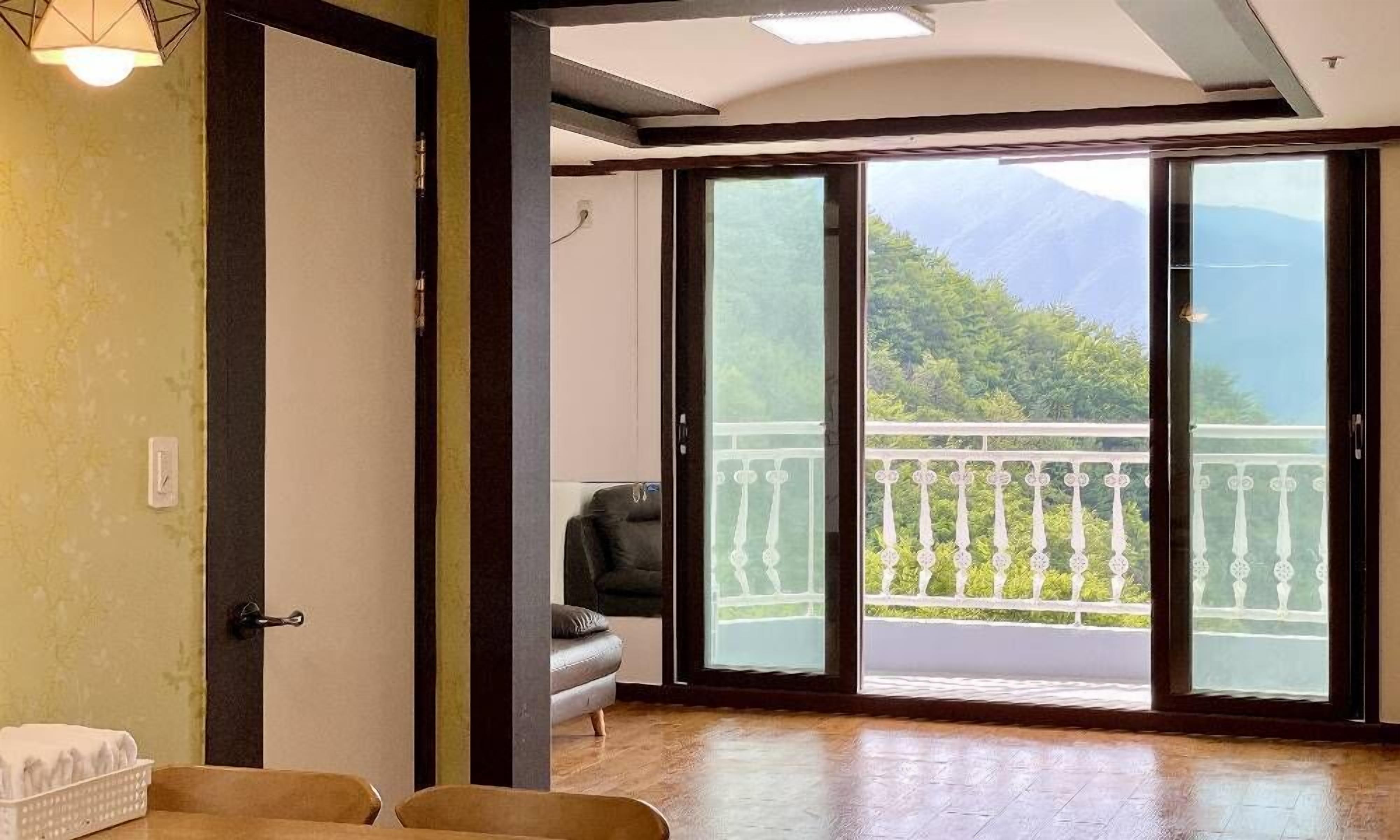 A room with a sliding glass door leading to a balcony with a mountain view.