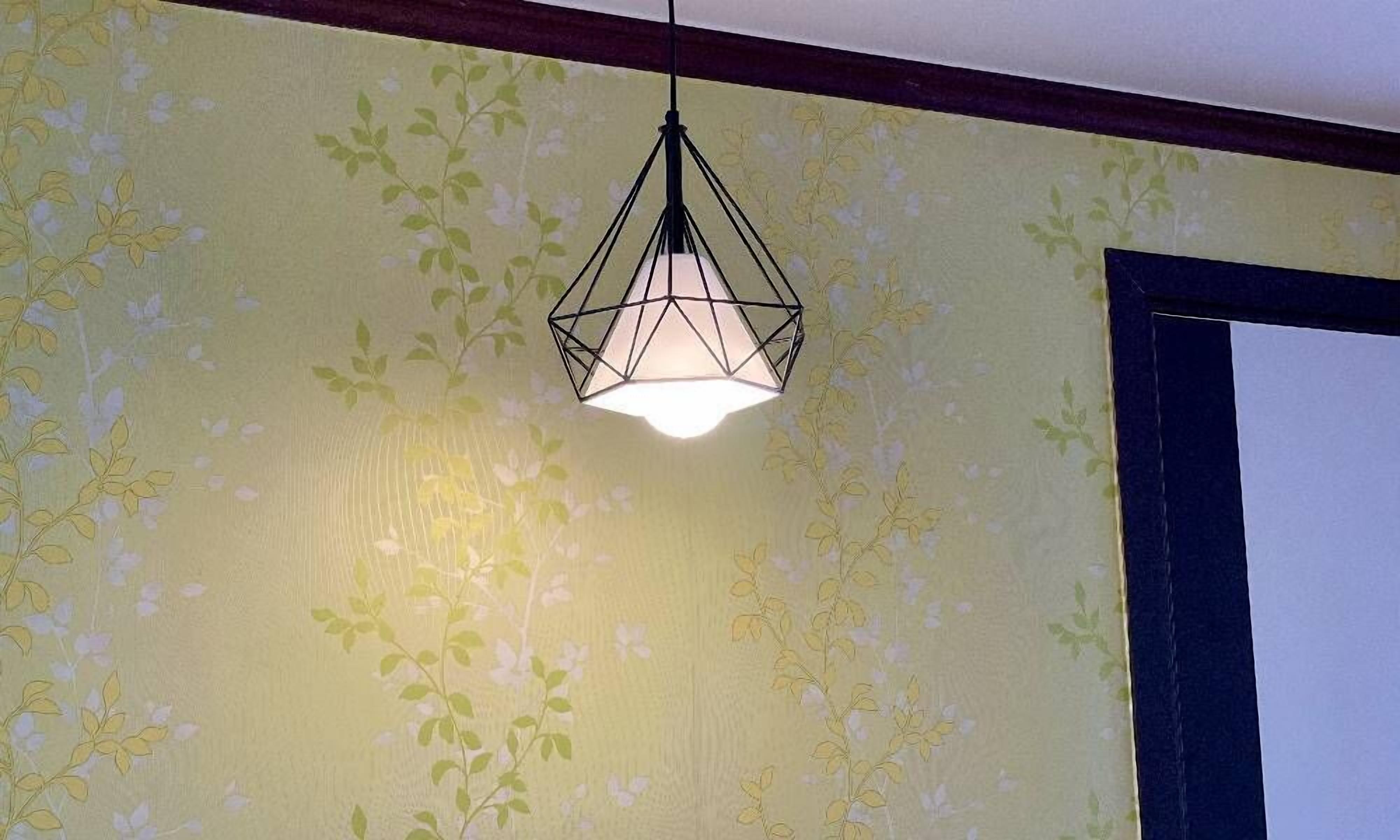 A room with floral wallpaper and a geometric pendant light.
