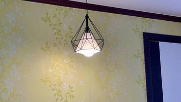 Una habitación con papel tapiz floral y una lámpara colgante de diseño geométrico.