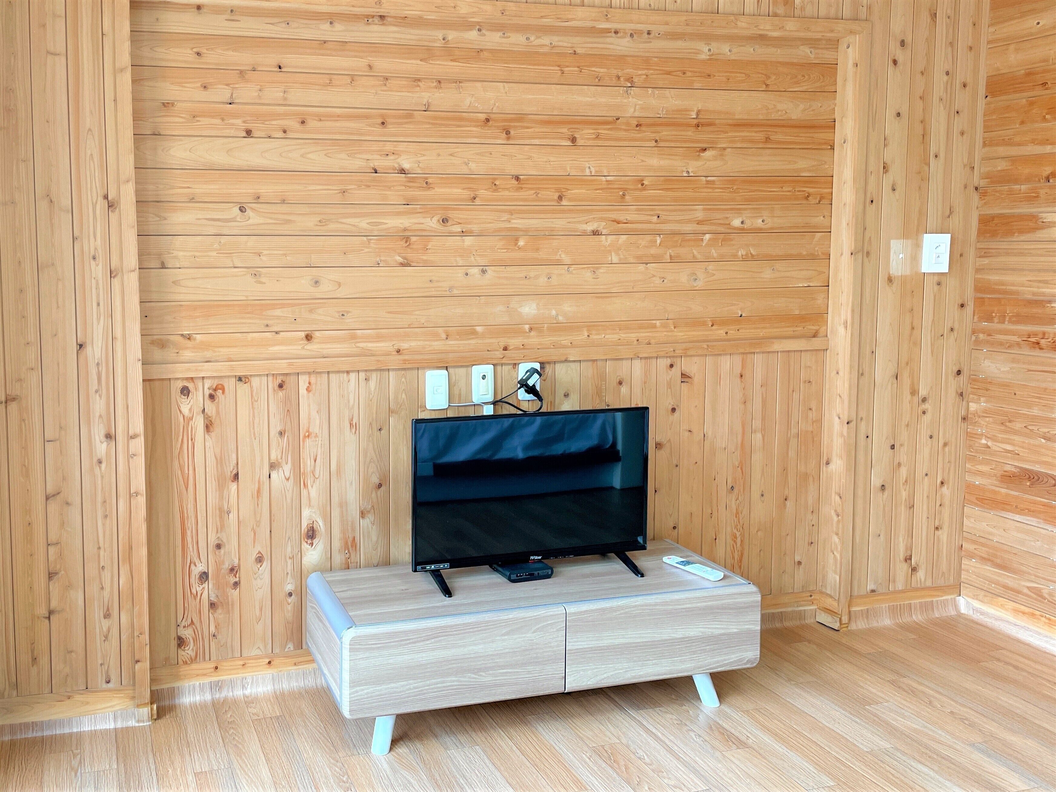 Una habitación con paneles de madera y un televisor de pantalla plana sobre un mueble de tonos claros.