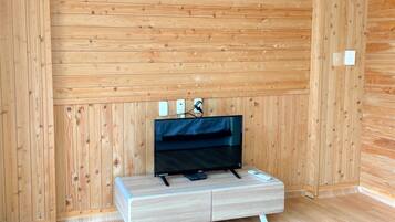 Una habitación con paneles de madera y un televisor de pantalla plana sobre un mueble de tonos claros.