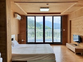 Una habitación de madera con cama, televisor y balcón con vistas a las montañas.