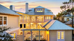 A two-story house with a covered patio, a chimney, and a balcony. - 'Rees on Wiregrass' | Private Pool, Golf Cart, Carriage House | Lake District, WaterColor, FL (Santa Rosa Beach)